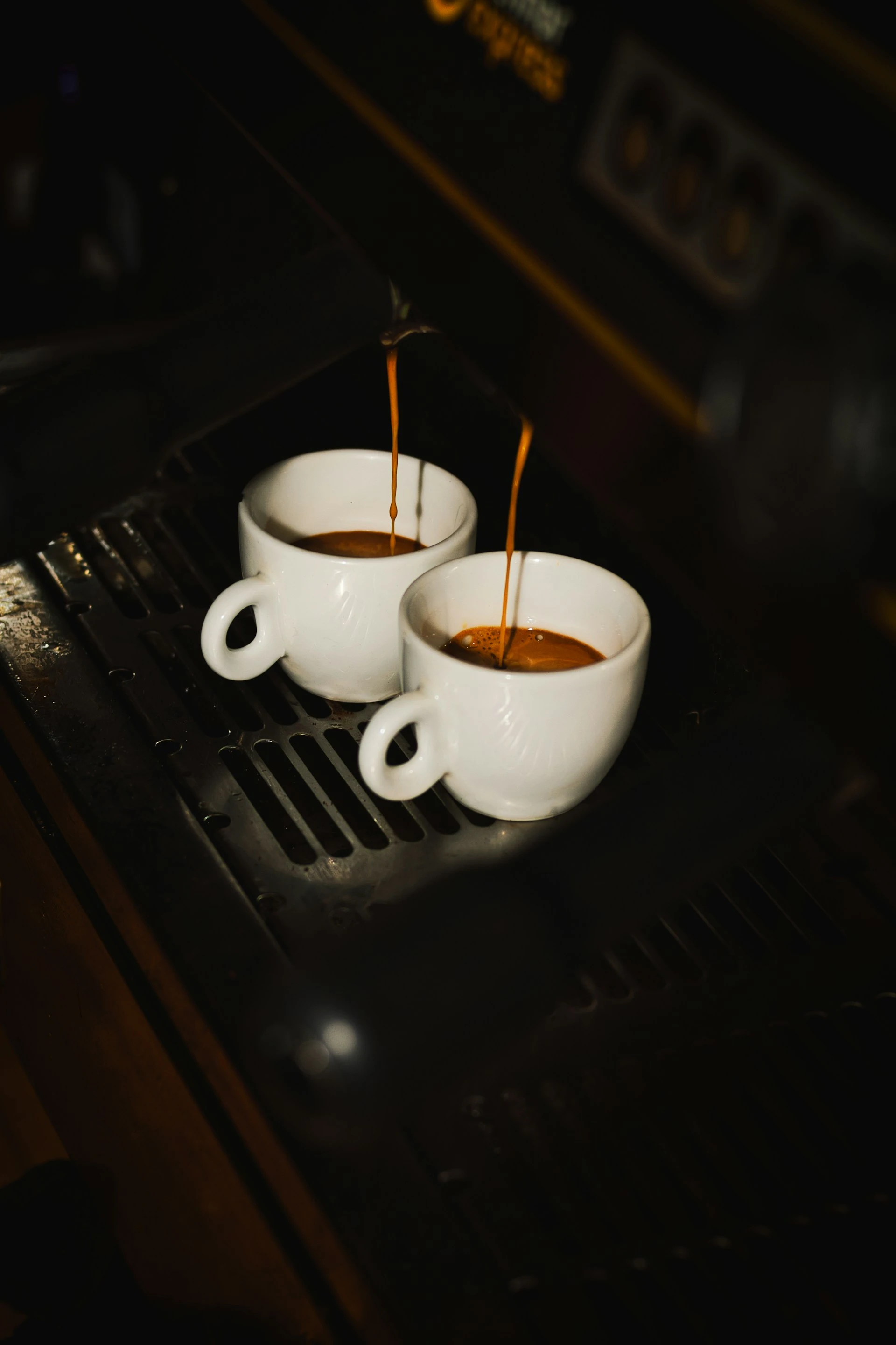 Espresso pouring into two white cups